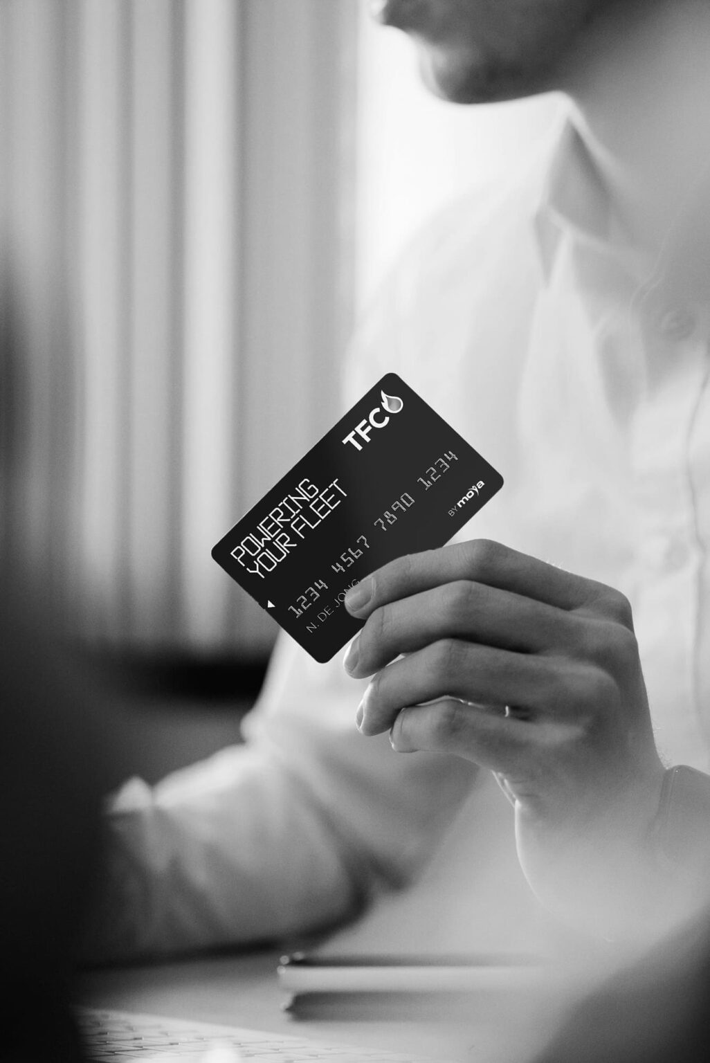Man sitting at a desk holding a TFC card. 